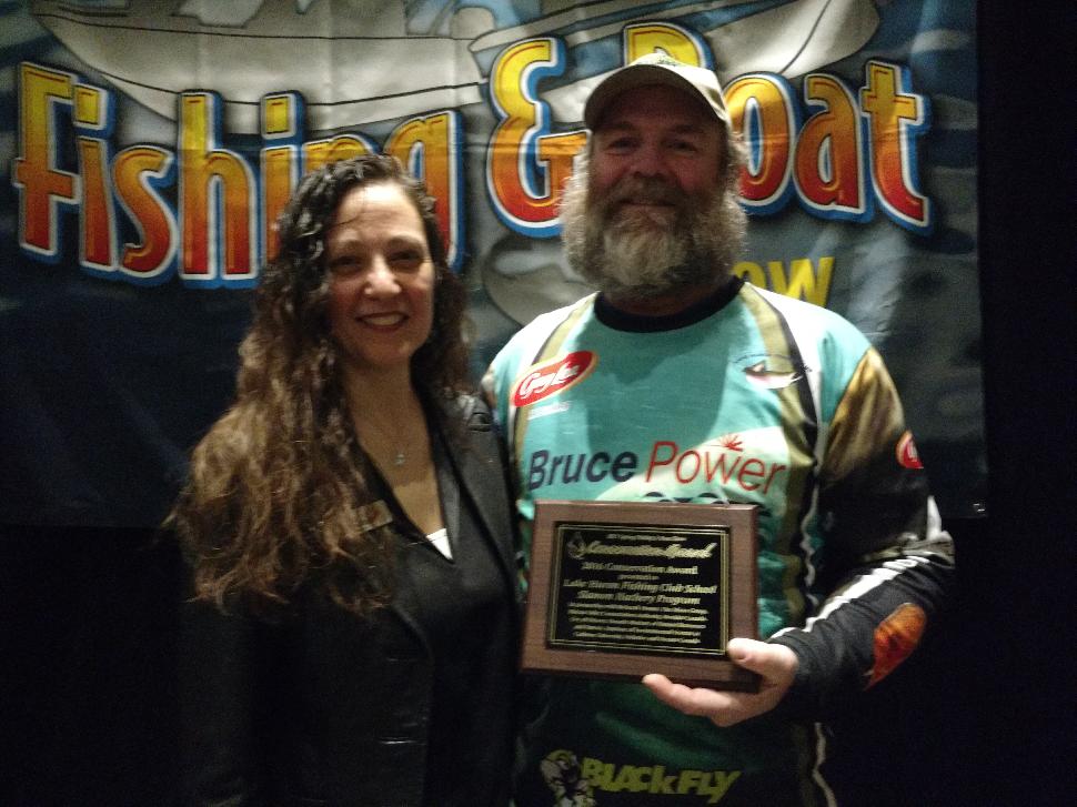 The Spring Fishing and Boat Show's Vita Pallotta congratulates Richard Elliott, organizer of the Lake Huron Fishing Club's School Salmon Hatchery Program, which earned the Conservation Project of the Year honour